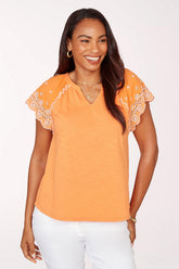 Woman wearing an orange top with lace sleeves on a white background