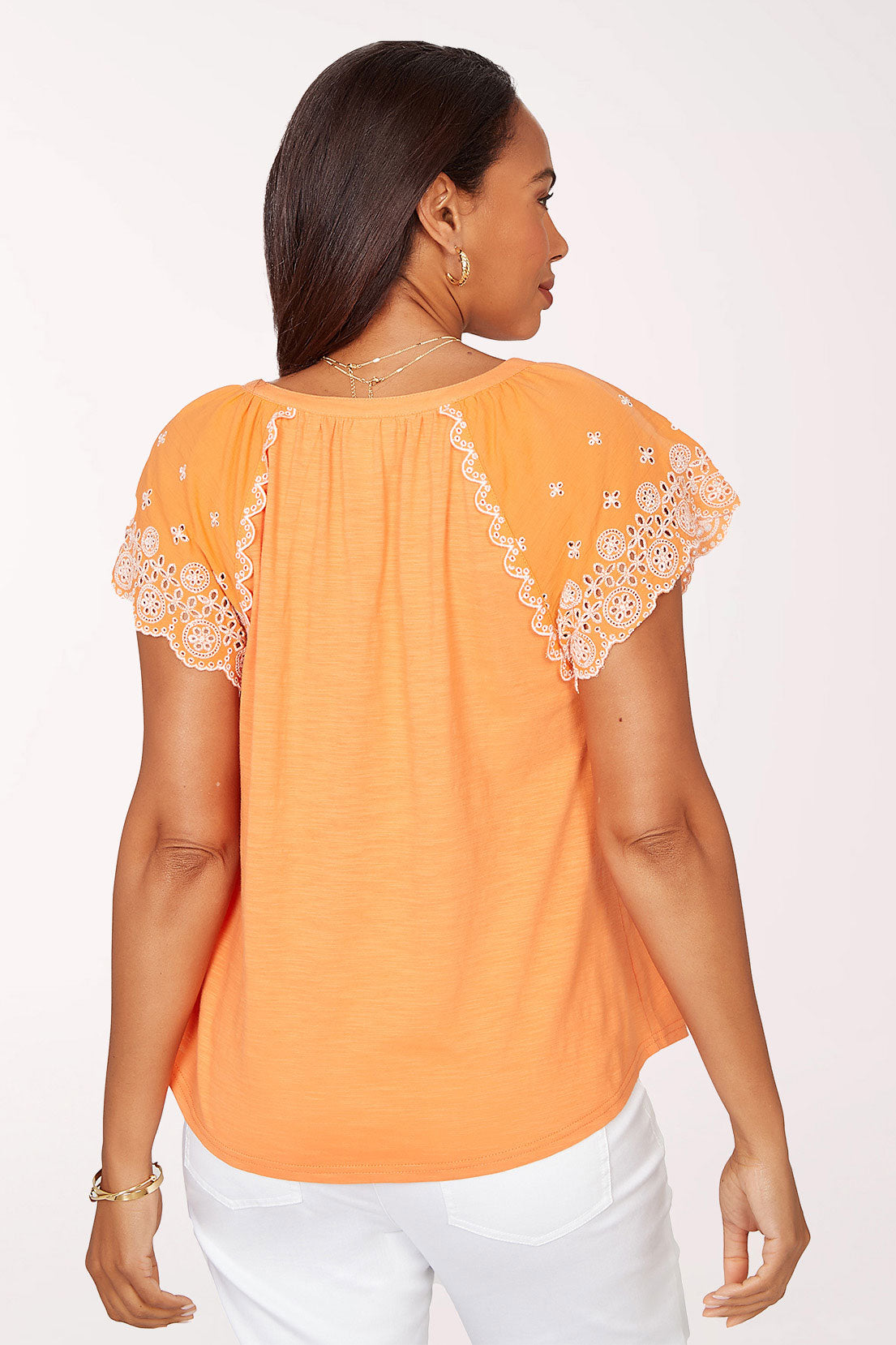 Woman wearing an orange top with lace sleeves on a white background