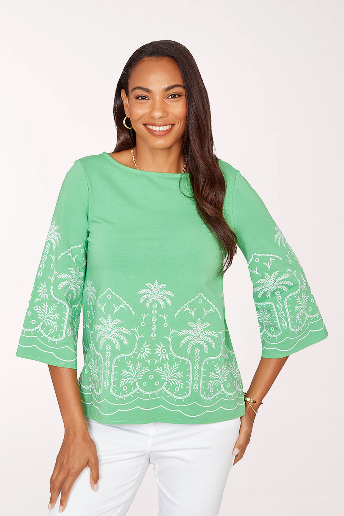 Woman wearing a green blouse with white palm tree patterns on a white background