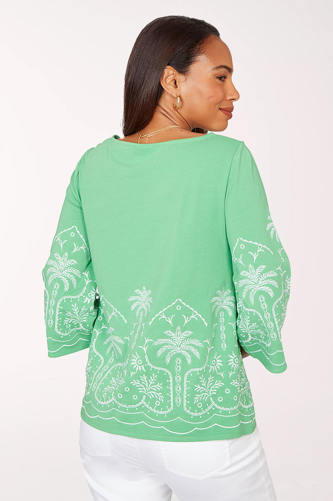 Woman wearing a green blouse with white palm tree patterns on a white background