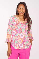 Woman wearing a colorful floral blouse and pink pants on a white background
