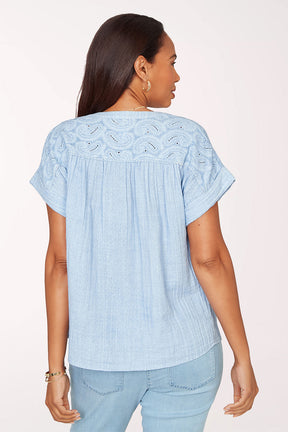 Woman wearing a short sleeve blue top.