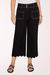 Person wearing black scalloped pants on a white background