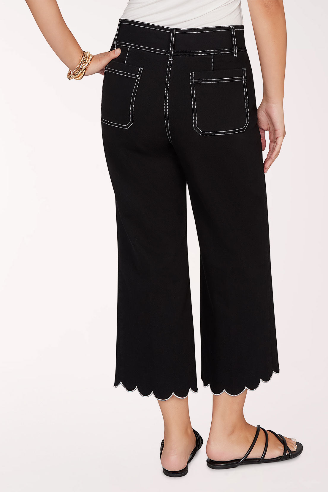 Person wearing black scalloped pants on a white background