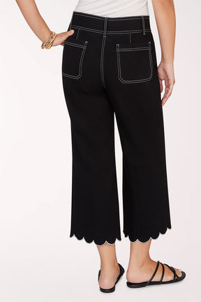 Person wearing black scalloped pants on a white background