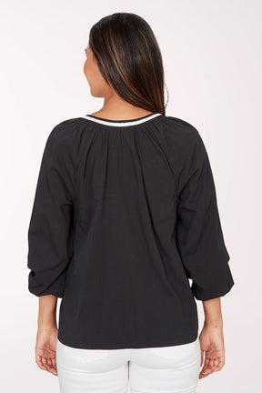 Woman wearing a black blouse with white embroidery on a white background