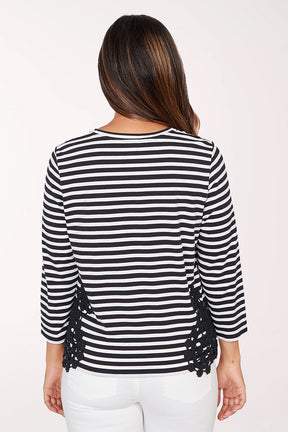 Woman wearing a black and white striped sweater with lace details on a white background