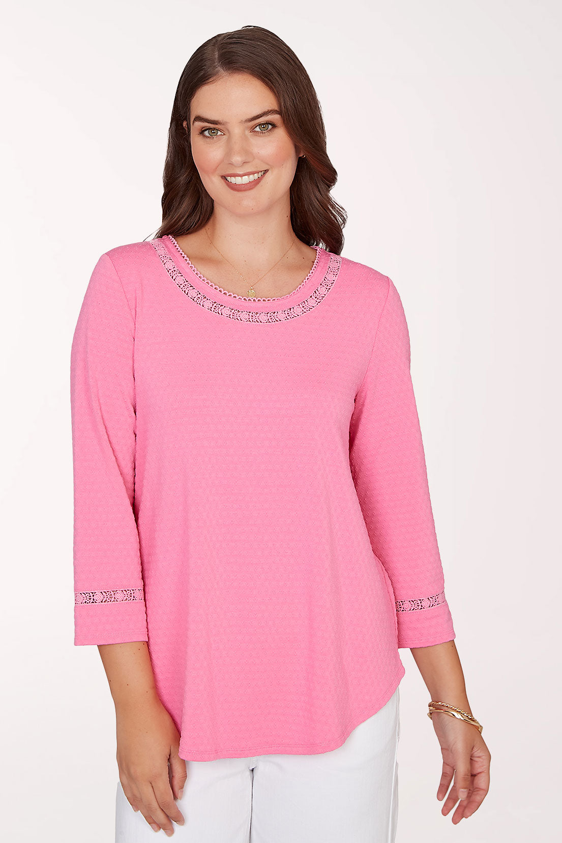 Woman wearing a pink blouse with lace details on a white background