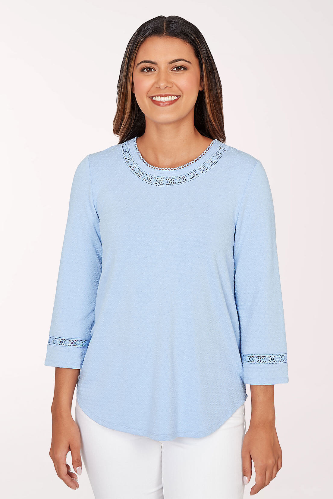 Woman wearing a light blue blouse with lace details on a white background