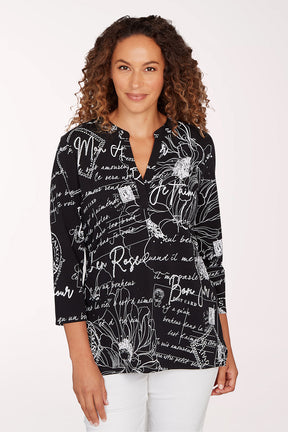 Woman wearing a black blouse with white text and floral patterns on a white background