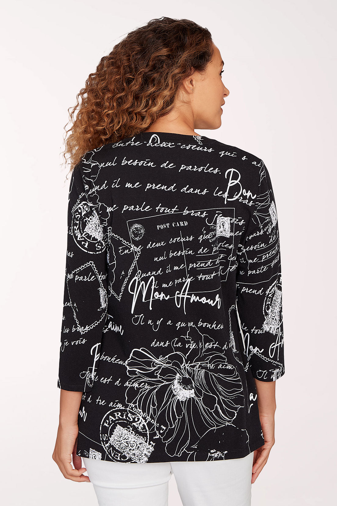 Woman wearing a black blouse with white text and floral patterns on a white background