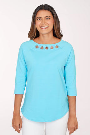 Woman wearing a light blue top with decorative buttons on a white background