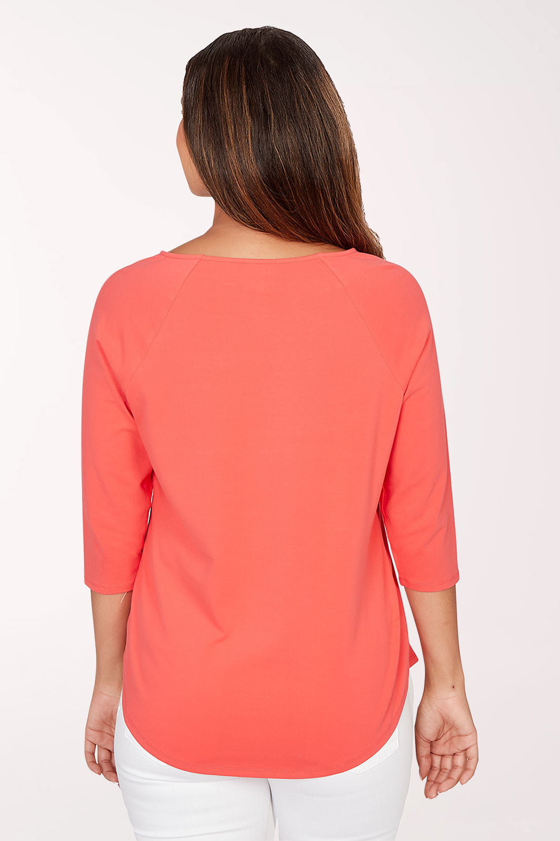 Woman wearing a coral top with decorative buttons on a white background