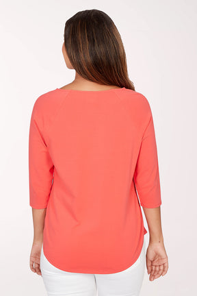 Woman wearing a coral top with decorative buttons on a white background