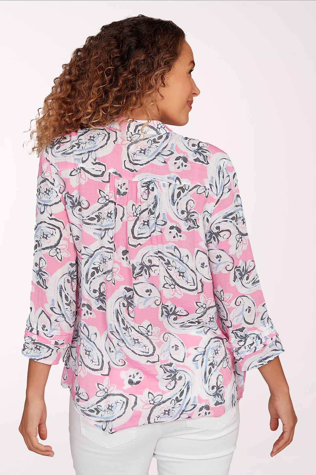 Woman wearing a pink and white patterned blouse on a white background