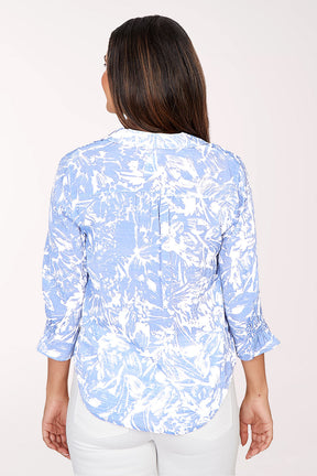 Woman wearing a light blue and white patterned blouse on a white background