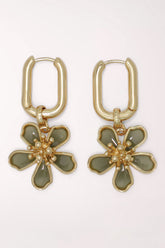 Pair of Periwinkle Blossom Charm Gold Huggie Hoop Earrings: rectangular gold-tone huggie hoops with dangling five-petal flower charms in sage green enamel, outlined in gold with a gold stamen center.