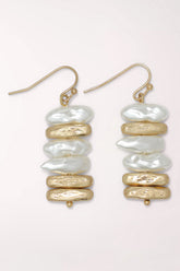 Pair of Periwinkle Brushed Gold And Pearl Stack Earrings on gold-tone French hooks: a column of flat, irregular faux pearl discs stacked between textured brushed gold discs, finished with a small gold bead.