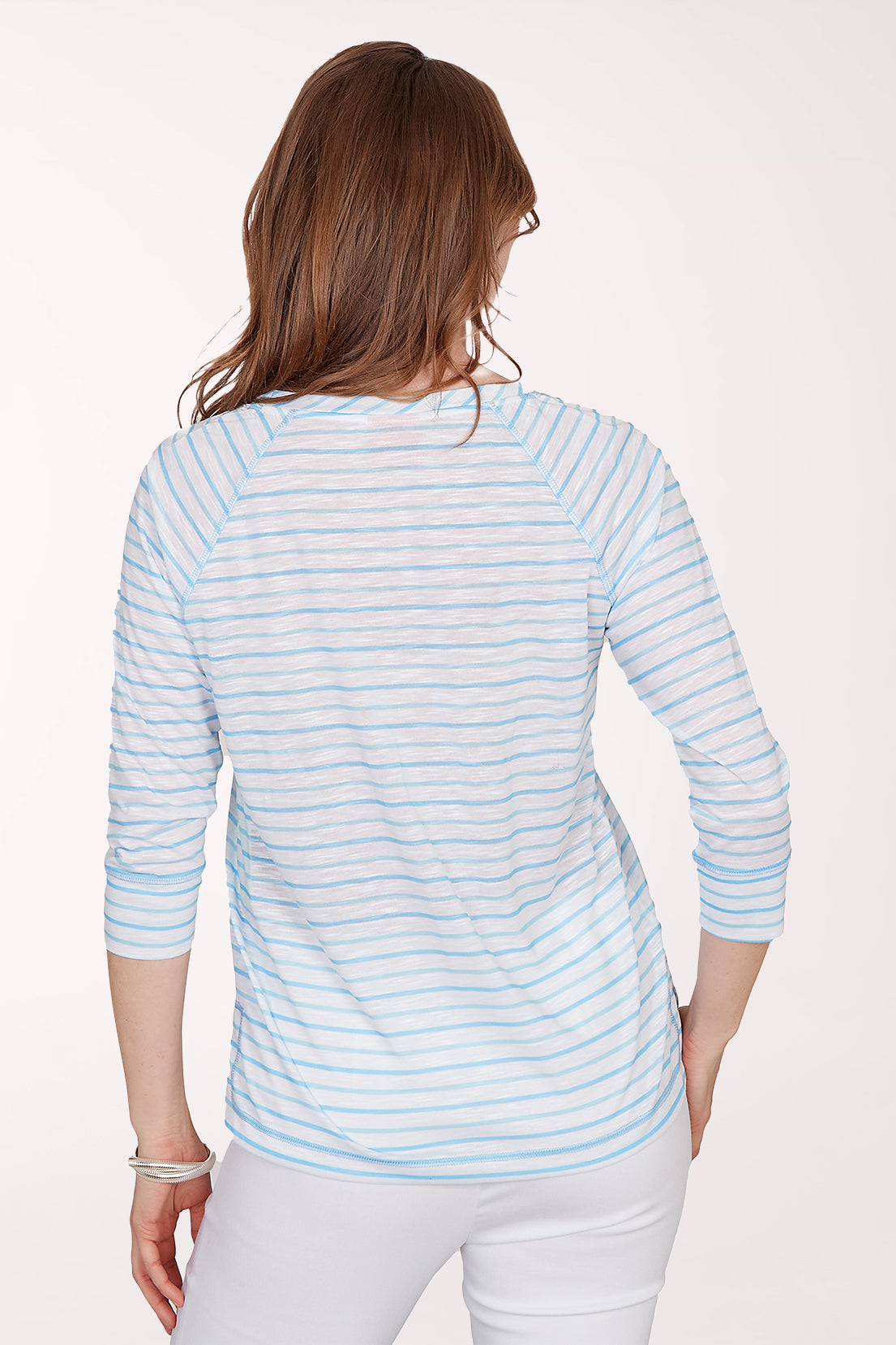 Woman wearing a light blue striped shirt with a floral design on a white background