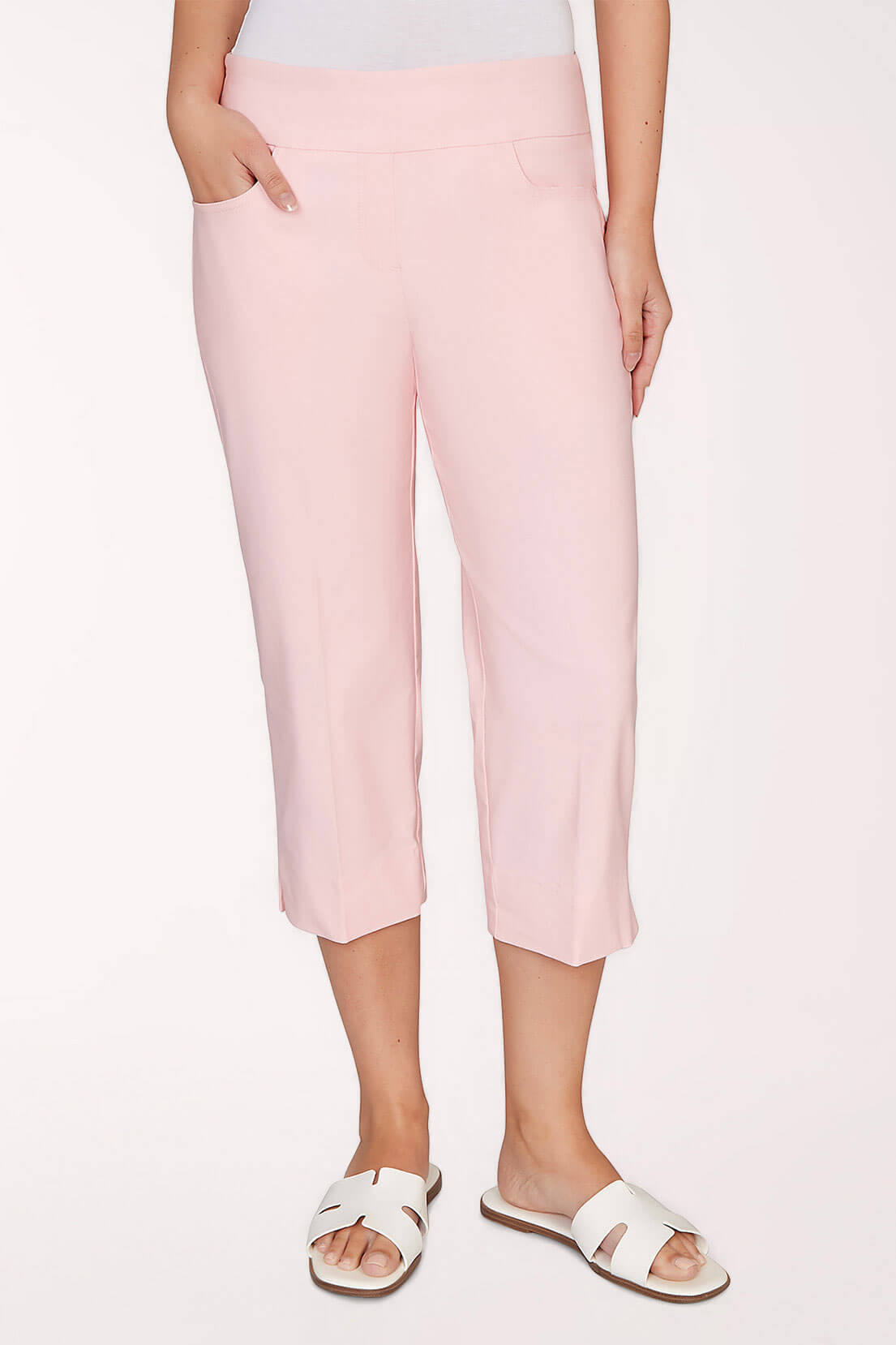 A woman wearing light pink capri pants against a light pink background