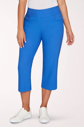 Person wearing blue capri pants and white sneakers on a light pink background