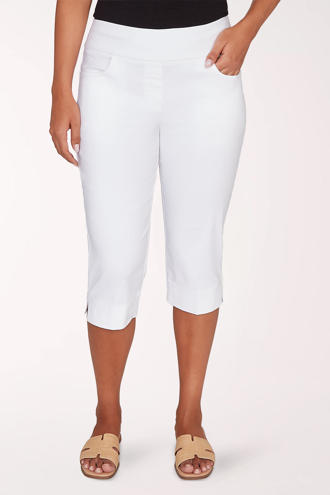 Person wearing white capri pants on a light pink background