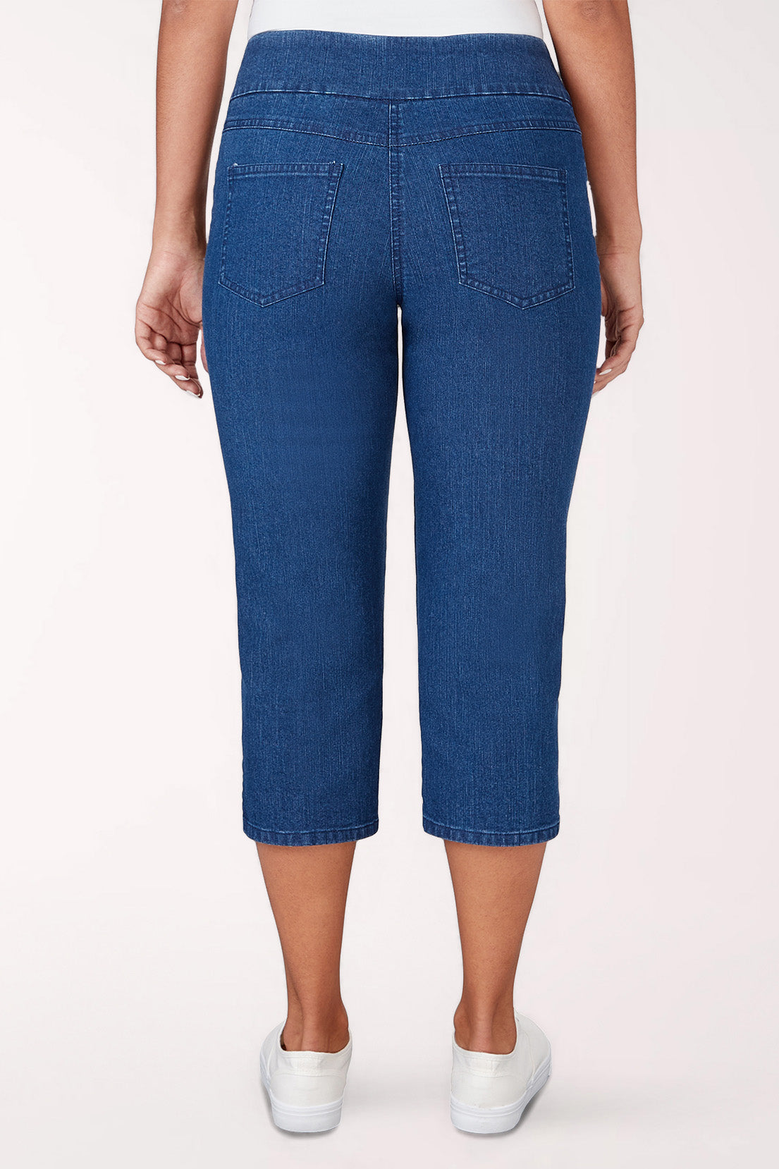 Person wearing blue denim capri pants on a white background