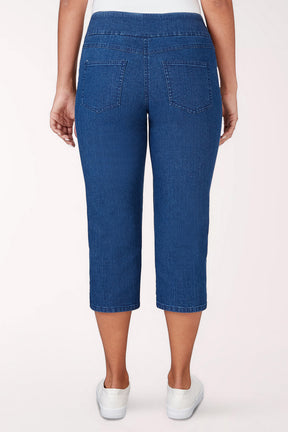 Person wearing blue denim capri pants on a white background