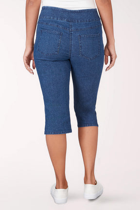 Person wearing blue denim capri pants on a white background