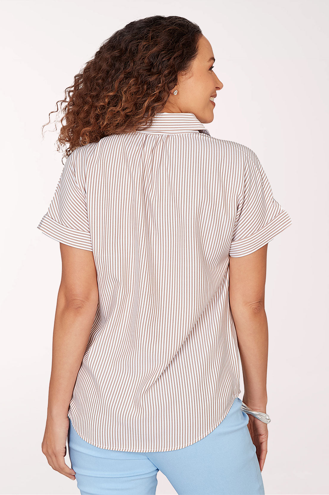 Woman wearing a striped shirt and light blue pants on a white background