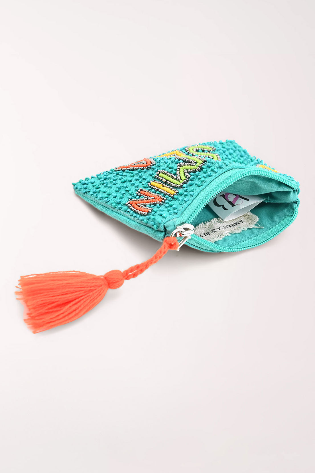 A turquoise beaded zip pouch with 'VITAMIN SEA' spelled out in colorful rhinestone letters and a bright orange tassel zipper pull, shown on a light gray background.
