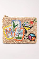 A small zip pouch covered in beige seed beads with colorful embroidered-style motifs including a cocktail glass, a cube, a letter M, and botanical cards.