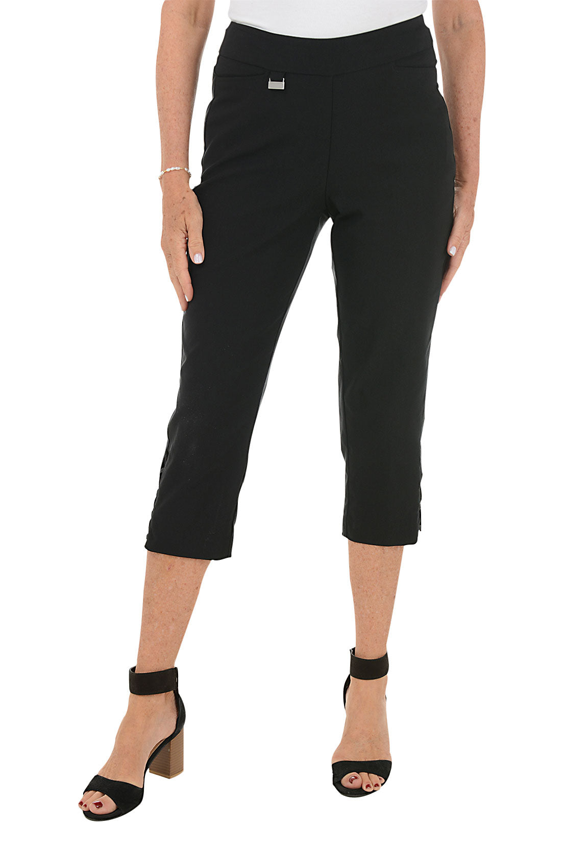 Person wearing black capri pants with lattice detail on side hem on a white background.