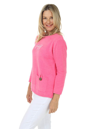 Side shot of a woman wearing a pink sweater with a logo on a white background