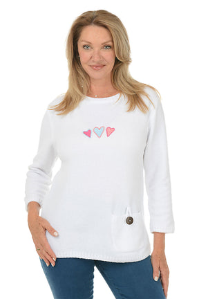 Woman wearing a white sweater with heart designs on a white background