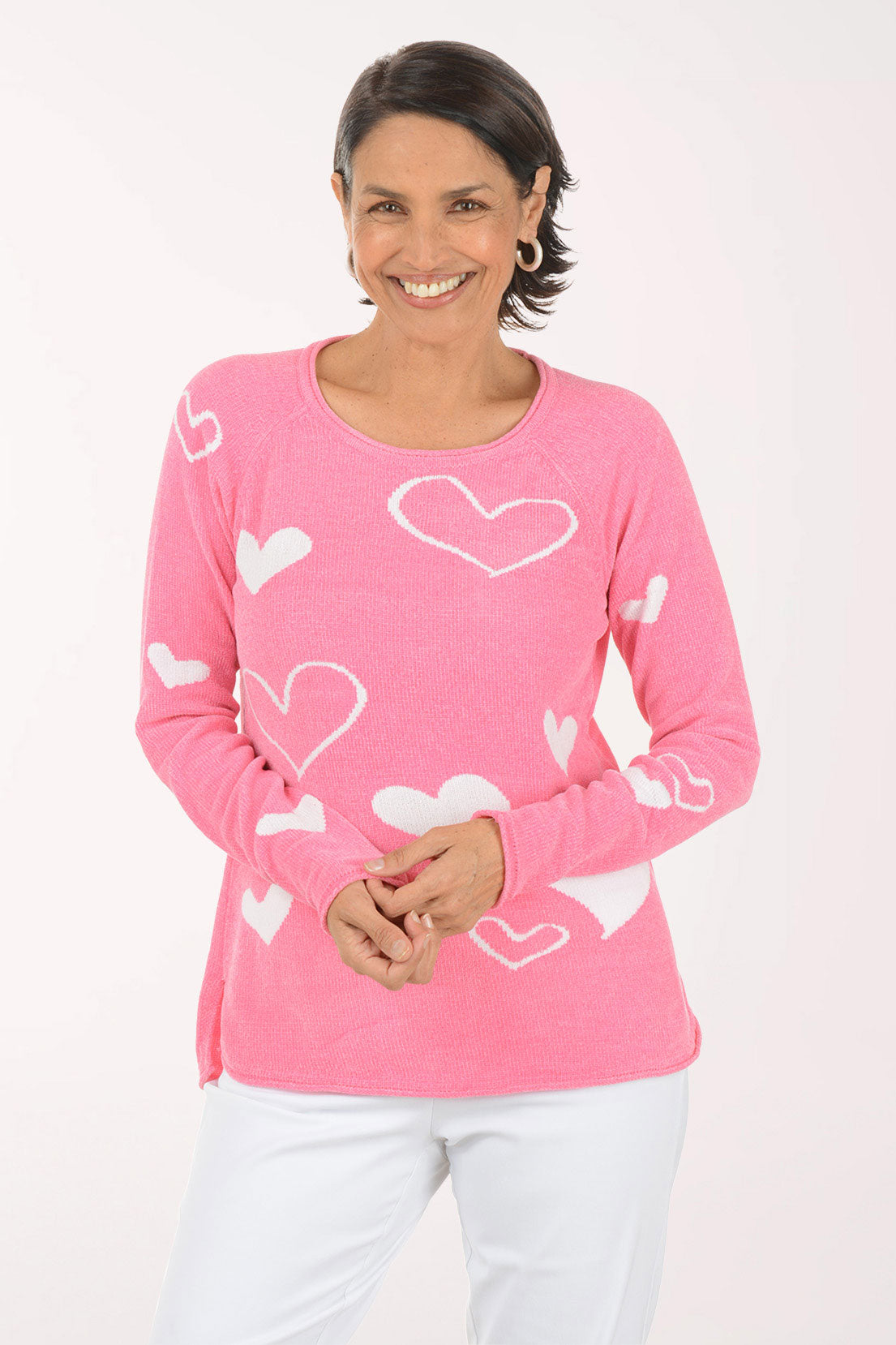 Woman wearing a pink sweater with heart patterns on a white background
