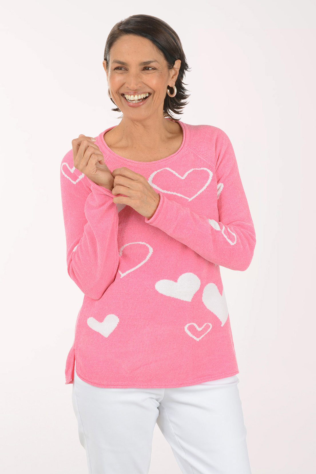 Woman wearing a pink sweater with heart patterns on a white background