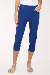 Front view of the Anthony's Resort Wear Crystal Lattice Hem Denim Capri Pant in bright cobalt blue stretch denim, with a wide pull-on waistband, front pockets and a crystal-studded lattice cutout at the outer hem, worn with a white top and silver sandals.
