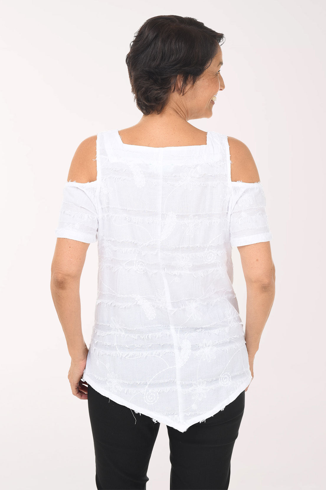 Woman wearing a white off-shoulder top and black pants on a white background