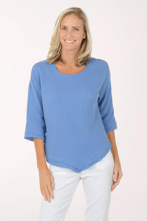 Woman wearing a blue top and white pants on a white background
