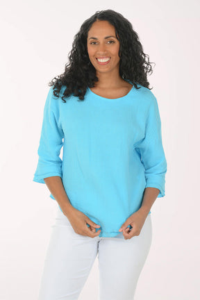 Woman wearing a light blue blouse and white pants on a white background