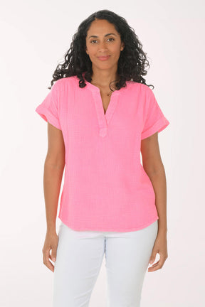 Woman wearing a pink blouse and white pants on a white background