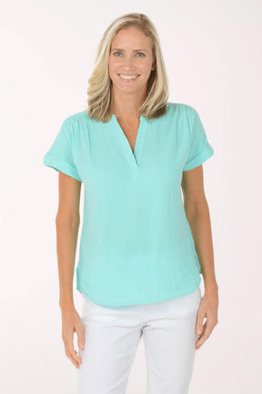 Woman wearing a light blue top and white pants on a white background