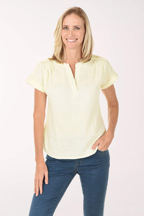 Woman wearing a light yellow blouse and blue jeans on a white background