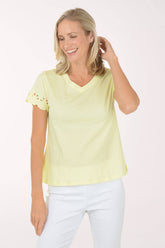 Woman wearing a light yellow top with white pants on a white background