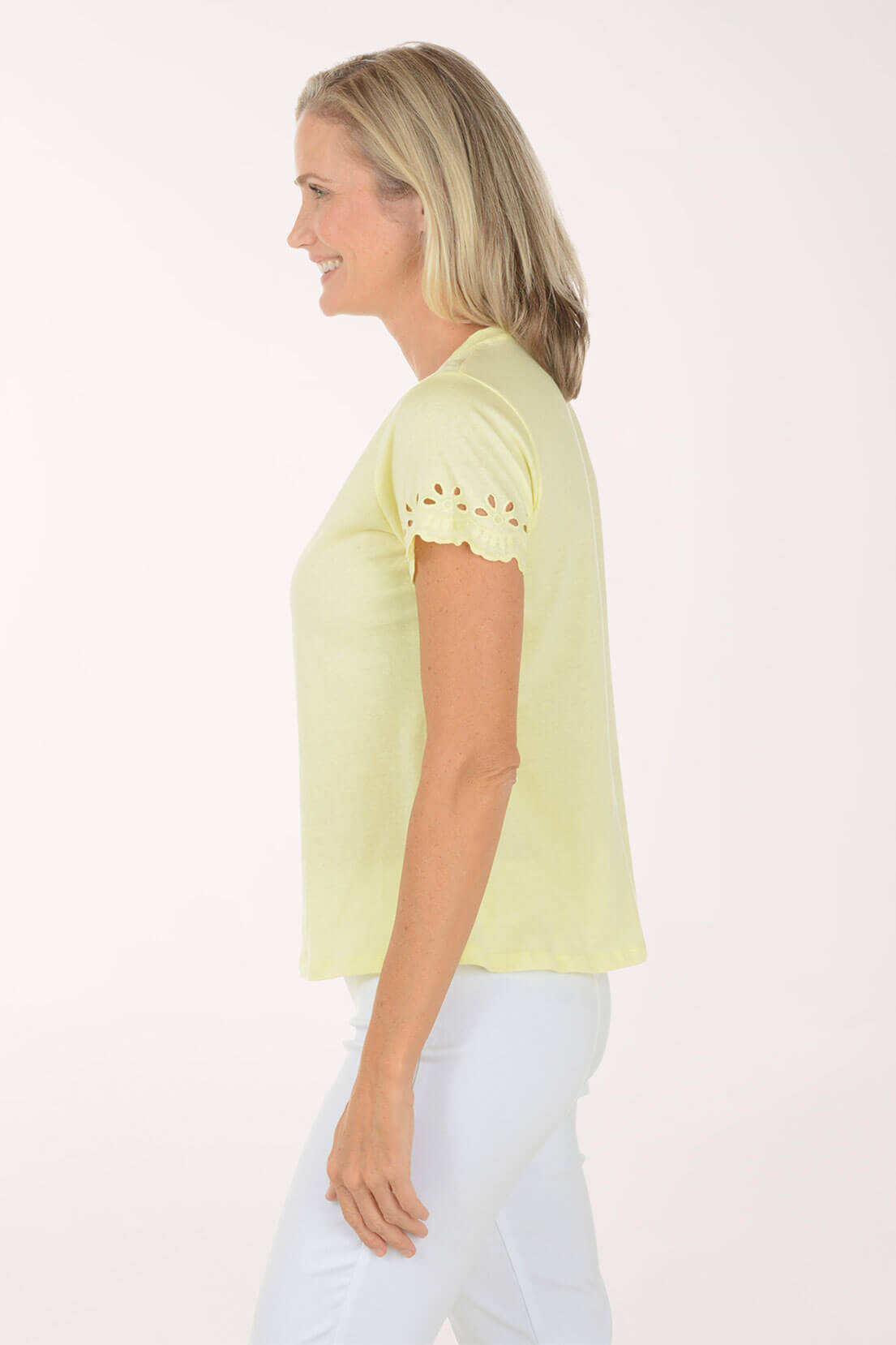 Woman wearing a light yellow top with lace details on a white background