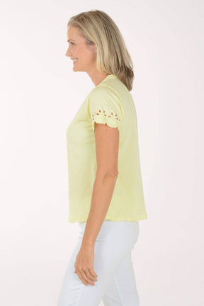 Woman wearing a light yellow top with lace details on a white background