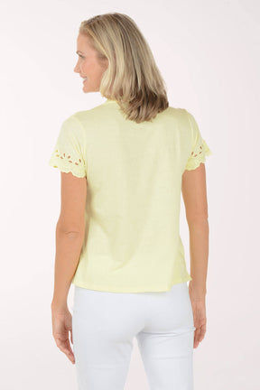 Woman wearing a light yellow top with lace details on a white background