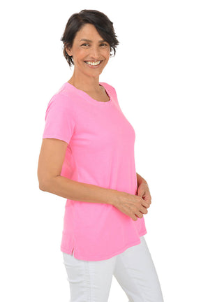 Woman wearing a pink shirt and white pants on a white background