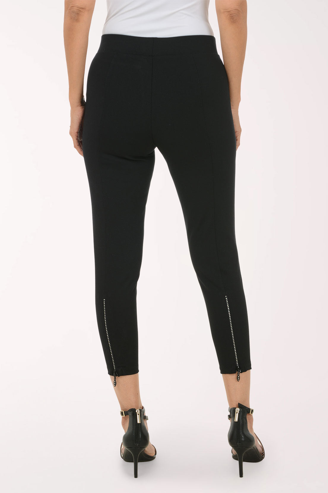 A model wearing black high-waisted cropped leggings and black strappy high-heeled sandals, shown from the waist down against a plain white studio background.